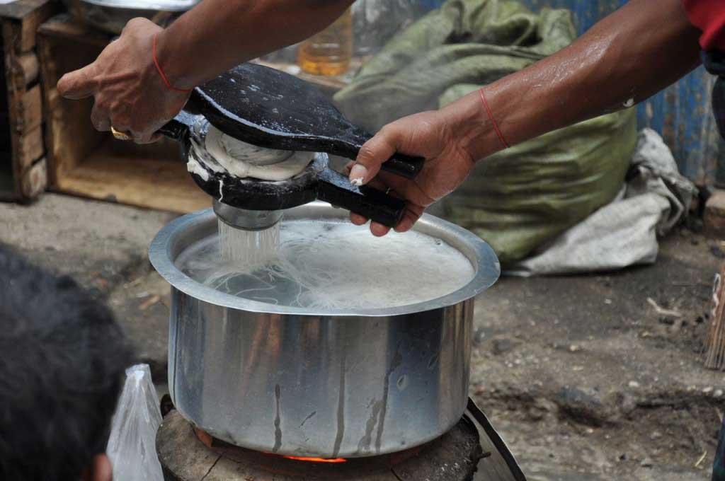 confecção de noodles numa das ruas de Yangon, onde a pasta feita à base de farinha de arroz e água é “espremida” através de um passador específico, para dentro de uma panela de água a ferver, ficando cozidos em pouco mais de um minuto