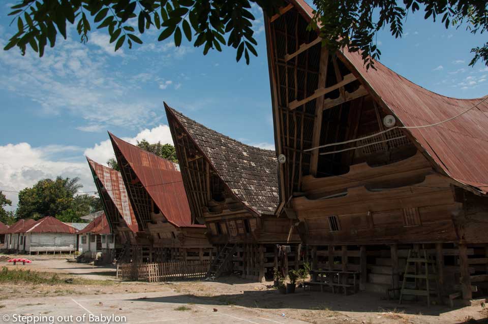 the Batak cultural identity is still visible in the characteristic architecture of the wooden houses with pointy and steep roofs, and proudly decorated with woodcarving motifs, painted in white, black and red